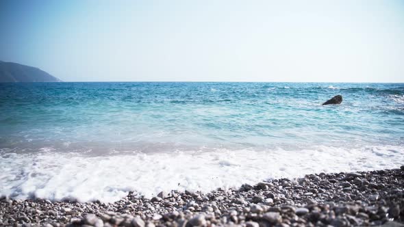 Cinematic Footage of an Empty Pebble Beach with Crystal Clear Blue Waves