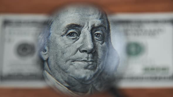 One Hundred Dollars Look Under Magnifying Glass on Wooden Table