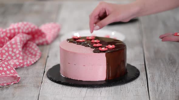 Female Hands Decorate Homemade Strawberry Mousse Cake with Sugar Flowers