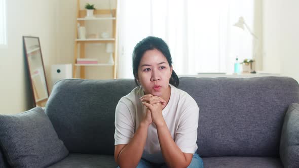 Asian business woman stressed with headache sitting on sofa in living room at house.