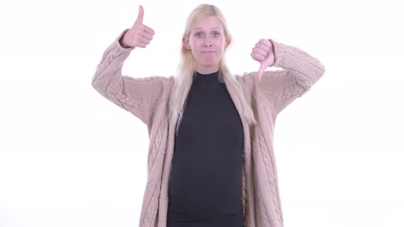 Confused Young Blonde Pregnant Woman Choosing Between Thumbs Up and Thumbs Down