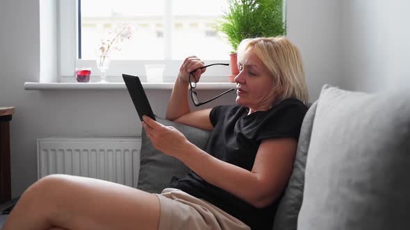 Mature Middle Age Woman Dealing Ebook at Home on the Couch