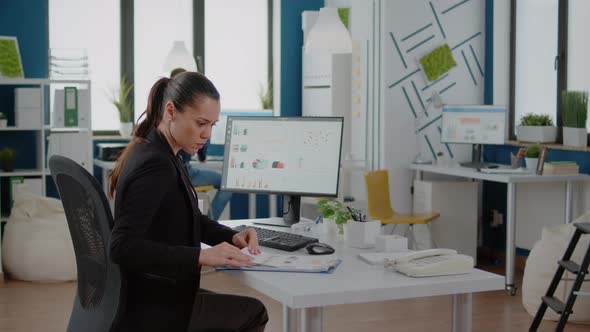 Businesswoman Working with Computer and Data Charts on Paper