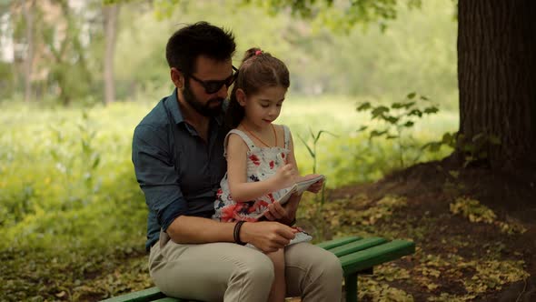 Preschool Child With Dad Learning Drawing Picture. Kid Sitting With Father And Draws On Notepad.