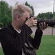 Male photographer takes photos on a professional camera outdoors in park. - VideoHive Item for Sale