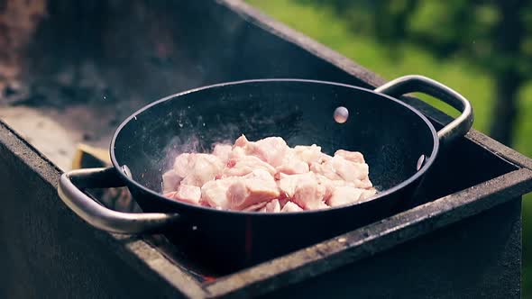 Close-up, Slow Motion: Pork Meat Is Fried in a Saucepan on Charcoal