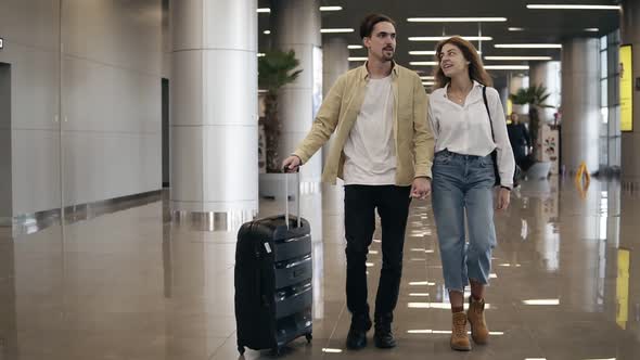 Front View of Smiling Couple Walking Together in Airport Going on Vacation or Trip