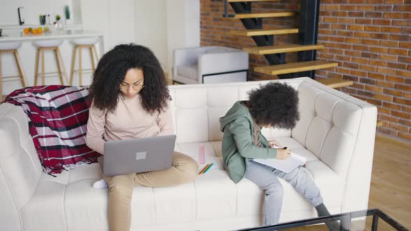 Mother and Son are Busy with Their Affairs Sitting on the Couch at Home