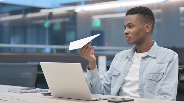 African Man with Laptop Flying Paper Plane