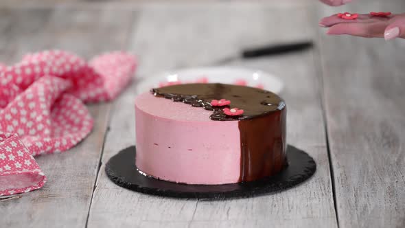 Female Hands Decorate Homemade Strawberry Mousse Cake with Sugar Flowers