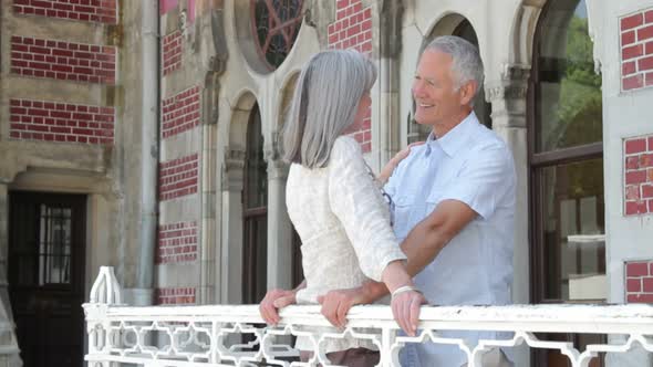 Senior couple sight seeing and embracing each other on balcony