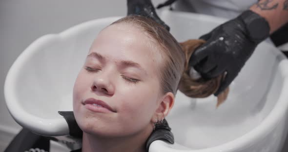 Hairdresser Rinsing Relaxed Woman'S Long Hair
