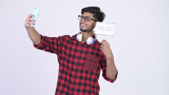 Young Happy Bearded Indian Hipster Man Taking Selfie with Paper Sign