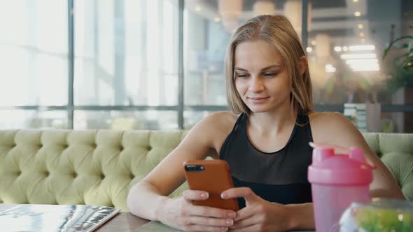 Beautiful Young Woman Is Sitting at Desk and Making Selfie on Smartphone Camera.