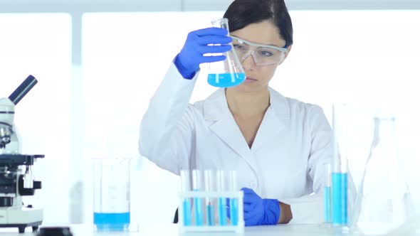 Scientist, Doctor Looking at Blue Solution in Flask in Laboratory