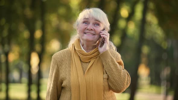 Smiling Old Woman Talking on Mobile Phone in Park, Full Family and Friends