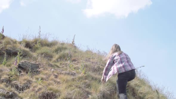 Woman climbing hill in rugged moorland medium landscape shot