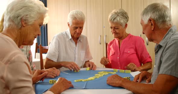 Senior friends talking while playing dominos