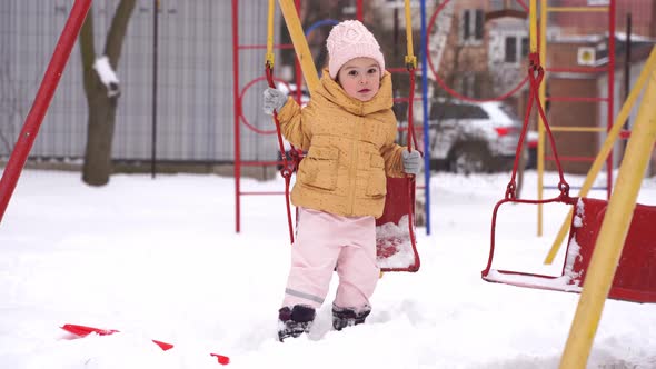 Toddler Girl Playing on Playground in Winter