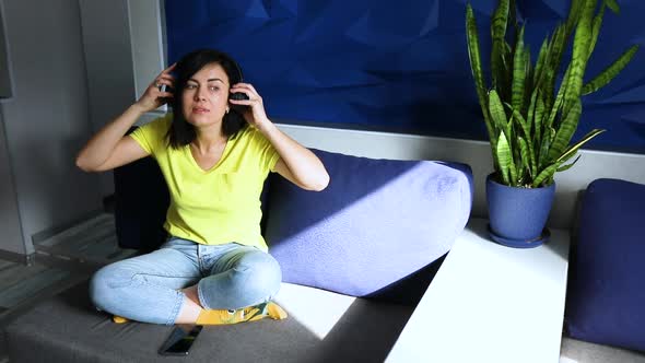 Slow motion woman in casual clothes put on headphones and click on smartphone, listening to podcast