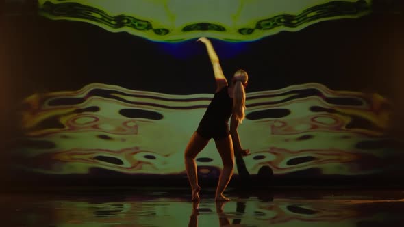 Artistic Young Woman Dancing Against Dark Animated Background on a Studios Stage