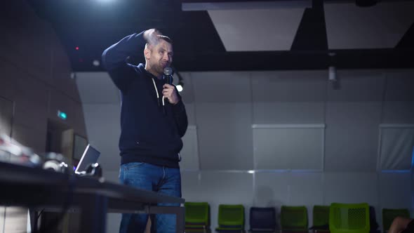 A Young Charismatic Man Makes a Presentation in a Dark Auditorium