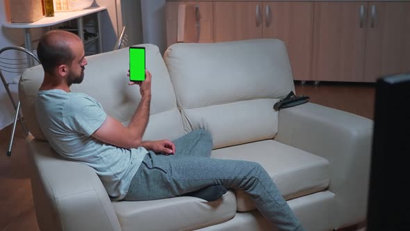 Caucasian Male Looking Phone with at Mock Up Green Screen Chroma Key Display