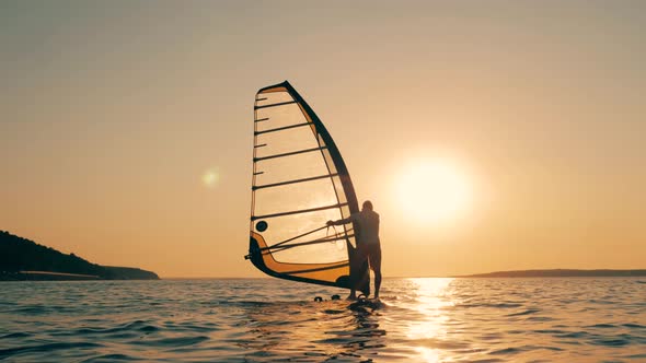 Sunset Sea and a Man Sailboading in It