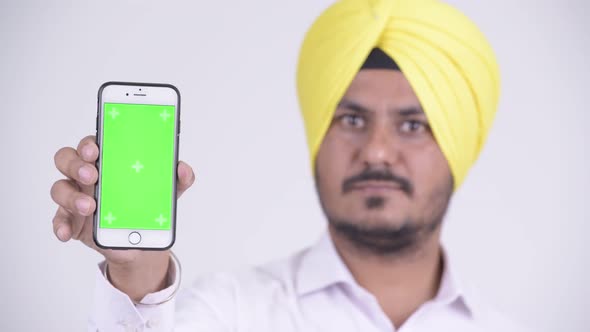 Face of Happy Bearded Indian Sikh Businessman Showing Phone