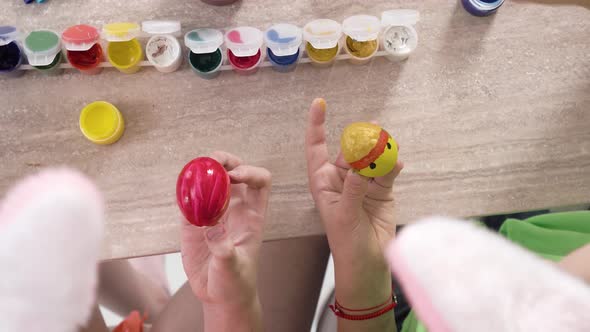 Top View of a Girl Decorating an Easter Egg Drawing a Yellow Chicken