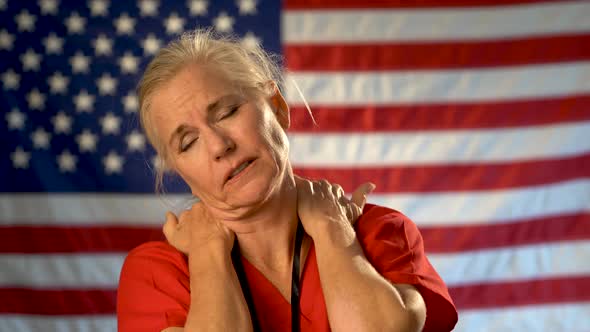 Medium tight portrait of nurse looking overwhelmed and stressed, hands on her neck with American fla