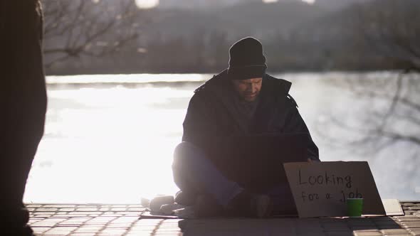 Homeless Bearded Male Begging and Using Laptop