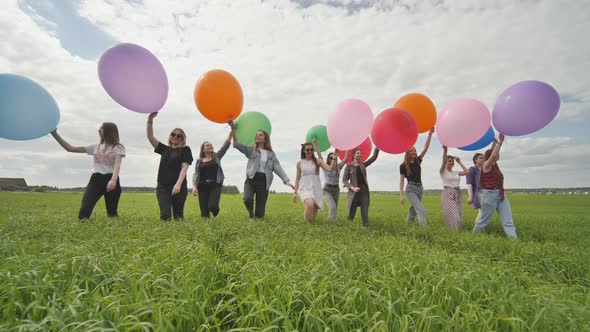 Girls Friends are Walking Across the Field with Large Balloons and Colorful Balloons