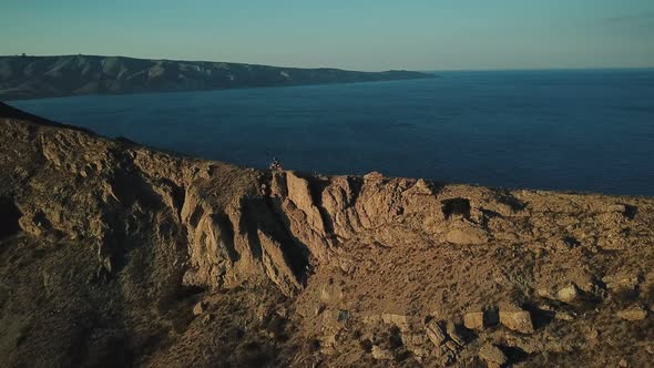 Drone View of Man on Motorbike Extremely Rides Across the Hills with Black Sea on Background in