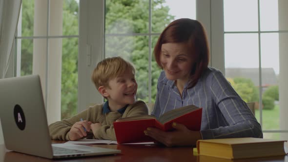 Young 30s Mother Reading Funny Book to Her Son at Home