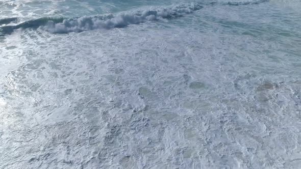 Medium waves crashing by beachfront