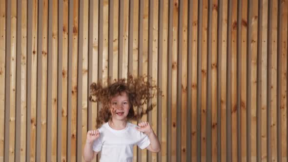 Preschooler Girl with Long Loose Curly Hair Jumps Up Smiling