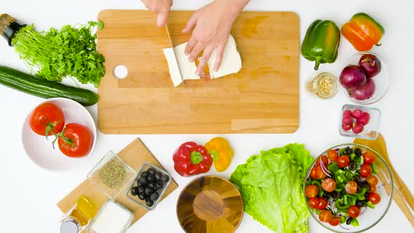 Woman with Knife Chopping Feta Cheese on Board