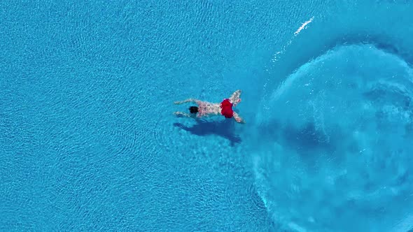 View From the Top As a Man Dives Into the Pool and Swims Under the Water