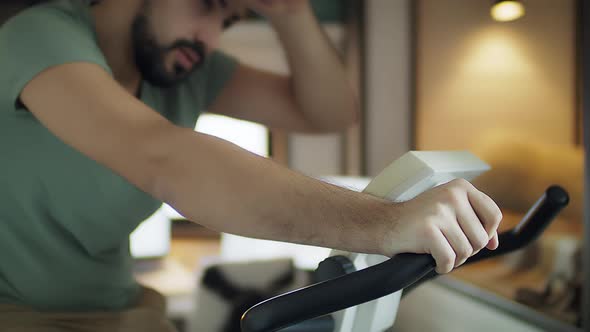 Young Male Working Out on Gym Bike at the Home