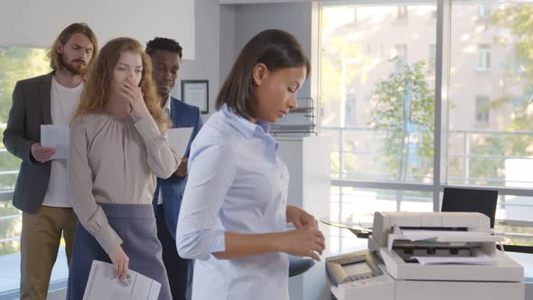 Group of Young Managers Standing in Queue for Copier at Office