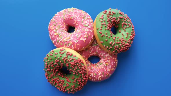 Top View Doughnuts with Colorful Icing Rotating Isolated on Blue