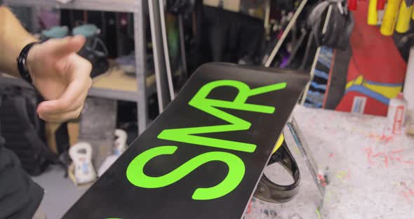 Repairman Is Polishing A Waxed Snowboard. Motion Toward And Backward