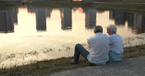 Hugs of an Elderly Couple on the Bank of the City Pond