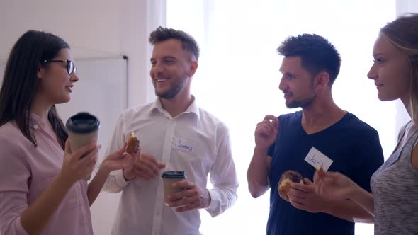 Happy Creative Team Communicate and Drinking Coffee with Cinnamon Buns During Break in Office