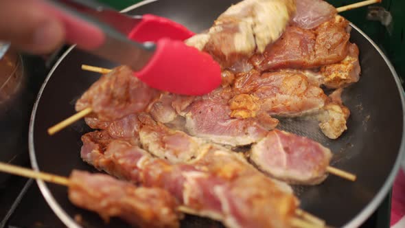 Frying delicious souvlaki skewers over a hot skillet.