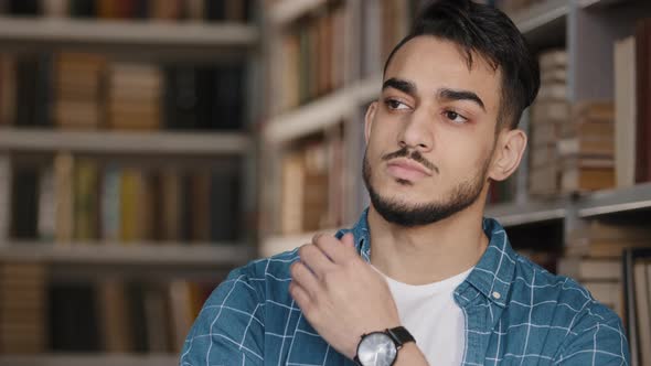 Thoughtful Serious Worried Young Hispanic Male Student Standing in Public University Library