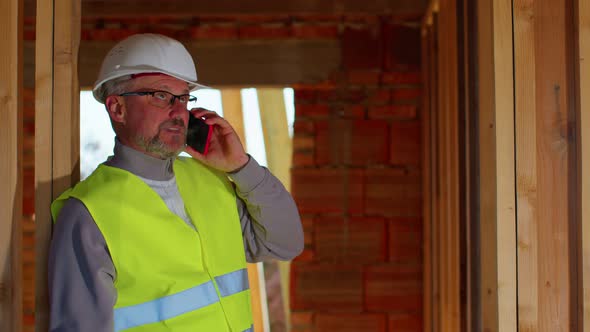 Civil Engineer Architect Specialist Talking on Mobile Phone to Control Working at Construction Site