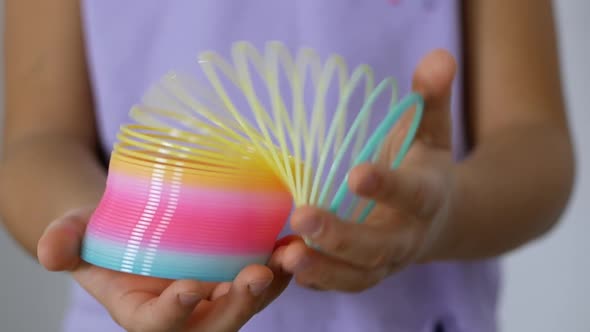 Kid holds a Slinky toy in his hands. A rainbow spiral for games popular in the '90s.