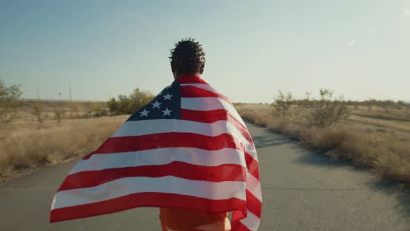 Confident Man Runs with an American Flag on His Back